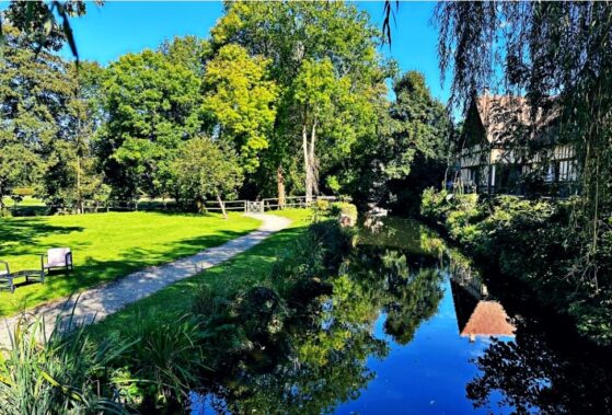 Paysage du Moulin de Chérotte à Damville avec un cours d'eau, des arbres et une maison à colombages, lieu de la fête des 25 ans de mariage de Martine et Didier Remy pour DJ Jakonet