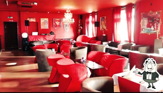 Intérieur de L'Antidote Lounge Bar à Neuchâtel avec des fauteuils rouges et une ambiance chaleureuse.